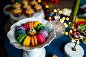 Rainbow Macarons on a white dish on a colourful table of birthday treats.