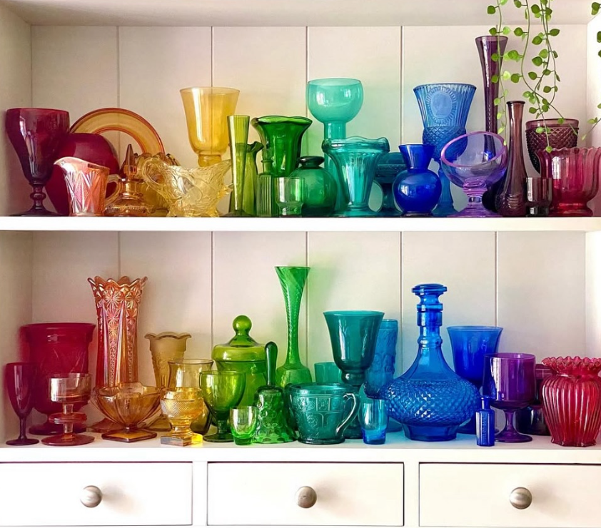 Brightly coloured vintage glassware collection, rainbow display on shelves